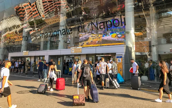 Napoli Havaalanı, İtalya - Ağustos 2019: Napoli Aiport 'taki terminal binasına bavul çeken insanlar.