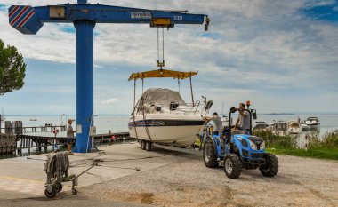 BARDOLINO, GARDA GÖLÜ, İTALYA - Eylül 2018: İşçiler Bardolino yakınlarındaki Garda Gölü 'ndeki bir marinada motorlu tekne taşımak üzereler.
