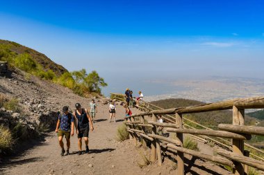 Vezüv Dağı, NAPLES 'ın yanında, İtalya - 2019 AĞUSTUSTOS: Otoparktan Vezüv Dağı' nın kraterine doğru yokuş yukarı yürüyen insanlar. Arka planda Napoli Körfezi var.