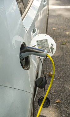 Londra, İngiltere - Haziran 2018: Elektrik prizine takılmış bir arabanın şarj olan kablosunun yakın görüntüsü.