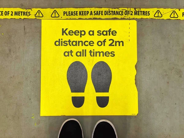Sign on floor of a store encouraging shoppers to maintain social distancing