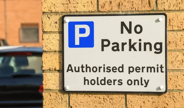 Sign on the wall of a building notifying drivers of a restricted parking area.