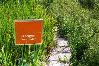 Bahçe manzaralı bir yol boyunca derin su uyarısı.