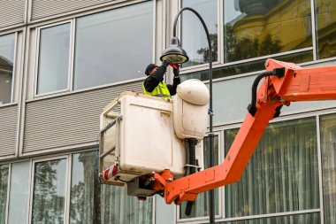 VIENNA, AUSTRIA - NOVEMBER 2019: Viyana şehir merkezinde bir sokak lambasına yenisini takan hidrolik kaldırma sepetinde çalışan işçi