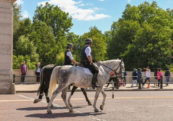 Londra, İngiltere - Temmuz 2018: Buckingham Sarayı 'nın dışındaki yolda iki polis atı, insanların nöbet değişimi için toplandığı.
