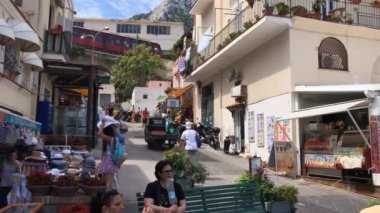 CAPRI, İtalya - Ağustos 2019: Capri, İtalya 'daki liman sokaklarından birindeki insanlar. Arka planda, Capri kasabasından füniküler bir tren geliyor..