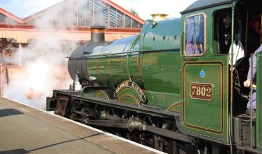 Kidderminster, İngiltere - Ağustos 2016: Kidderminster 'daki platformda motorun önünde beyaz buhar bulutları bulunan bir buharlı lokomotifin geniş açı görünümü