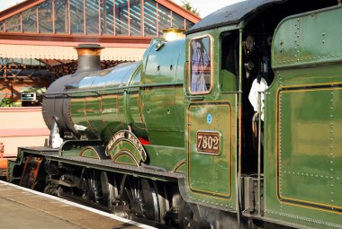 Kidderminster, İngiltere - Ağustos 2016: Kidderminster 'daki platformda motorun önünde beyaz buhar bulutları bulunan bir buharlı lokomotifin geniş açı görünümü