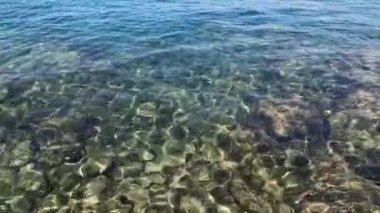 Güneş ışığında, deniz tabanında kayalarla sığ sularda hafif dalgalanmalar. 