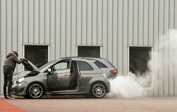 MONACO,EUROPE - JANUARY 2018: A driver looking at the engine of a car with white smoke blowing from the exhaust