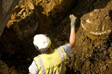 Pontypridd, Galler - Mayıs 2018: Eski bir alışveriş merkezinin şantiyesinde önemli bir gelişme olan Şekerleme Vadisi yenilenme projesinin temellerini kazan bir kazıcı yöneten inşaat işçisi.