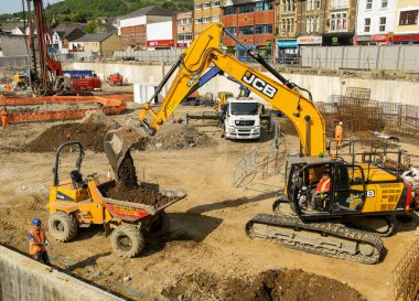 Pontypridd, Galler - Mayıs 2018: Şekerleme Vadisi yenilenme projesi üzerinde çalışan kazıcı, eski Taff Vale Bölgesi 'nin şantiyesinde büyük bir yeni karma kullanım geliştirmesi..