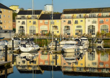 Penarth Marina, Cardiff Körfezi, Galler - Mayıs 2018: Pastel renklerle boyanmış apartman bloklarının önünde Penarth Marina 'da demirlemiş motorlu botlar.