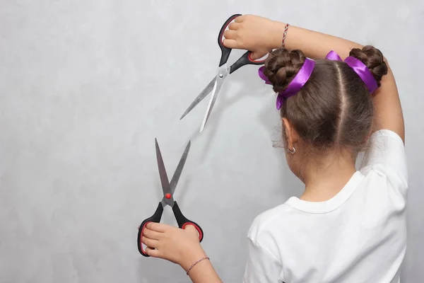 Hairstyle and haircare concept. Hairdressing services. Girl holding scissors. Hair with ribbons.