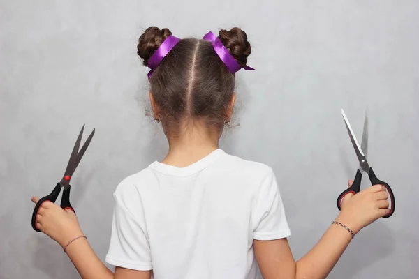 Hairstyle and haircare concept. Hairdressing services. Girl holding scissors. Hair with ribbons.