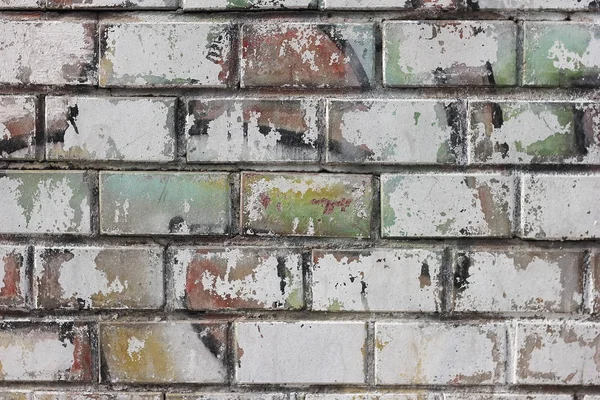 Brick wall with a worn-out pattern and traces of old paint. Background and texture.