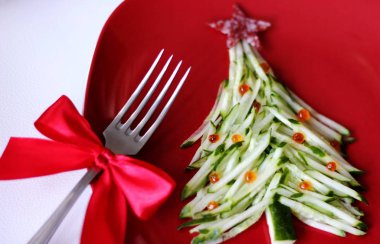 Christmas tree is made of sliced cucumber and decorated with red caviar. New years design of dishes. New years food. Food for the new year holiday. Decoration of dishes. Red plate. clipart