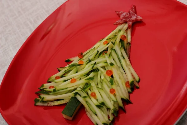 Christmas tree is made of sliced cucumber and decorated with red caviar. New years design of dishes. New years food. Food for the new year holiday. Decoration of dishes. Red plate. — Stock Photo, Image