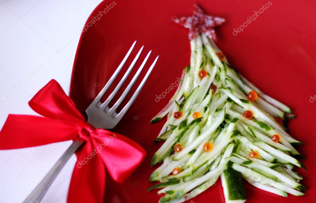Christmas tree is made of sliced cucumber and decorated with red caviar. New years design of dishes. New years food. Food for the new year holiday. Decoration of dishes. Red plate.