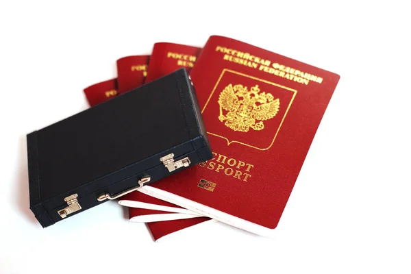 Den Reisepass der Russischen Föderation. Biometrische russische Pässe liegen um einen Miniaturkoffer auf weißem Hintergrund herum.. — Stockfoto