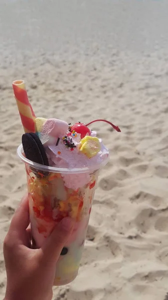 Mooie smakelijke ijs in de hand tegen het zand op het strand in de zomer — Stockfoto