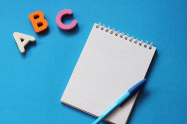Abc-mavi bir arka plan üzerinde İngiliz alfabesinin ilk harfleri. Defter ve kalem. Metin için boş alan. Yabancı dil öğrenin.