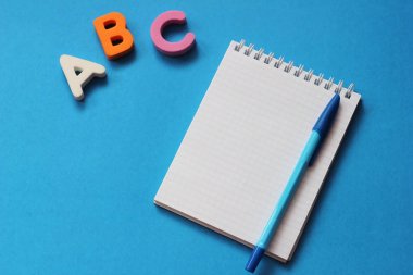 Abc-mavi bir arka plan üzerinde İngiliz alfabesinin ilk harfleri. Defter ve kalem. Metin için boş alan. Yabancı dil öğrenin.