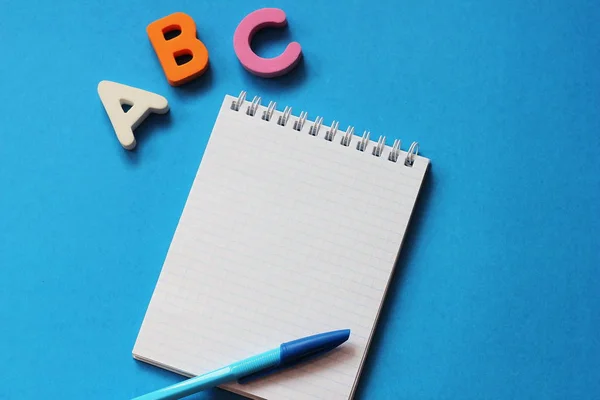 ABC-de första bokstäverna i det engelska alfabetet på en blå bakgrund. Anteckningsbok och penna. Tomt utrymme för text. Lär dig främmande språk. — Stockfoto