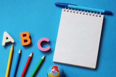 Abc-mavi bir arka plan üzerinde İngiliz alfabesinin ilk harfleri. Defter ve kalem. Metin için boş alan. Yabancı dil öğrenin.