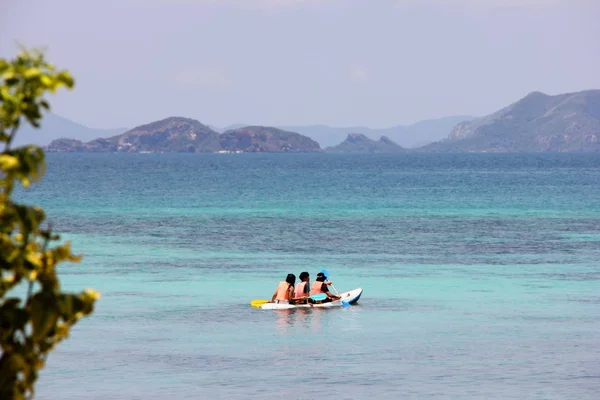 Tourists in life jackets kayaking in the clear blue sea.