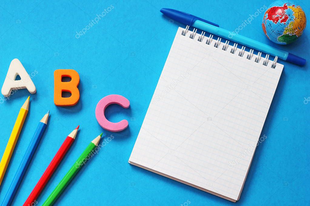 ABC-the first letters of the English alphabet on a blue background. Notebook and pen. Empty space for text. Learn foreign languages.