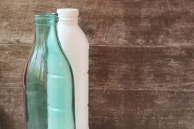 Cam süt şişesi ve plastik şişe. Yeniden kullanılabilir ambalaj. Metin için boş alan.