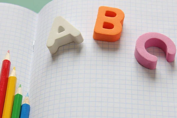 ABC-le prime lettere dell'alfabeto inglese e matite colorate sul taccuino della scuola . — Foto Stock