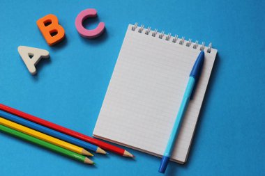 Abc-mavi bir arka plan üzerinde İngiliz alfabesinin ilk harfleri. Defter ve kalem. Metin için boş alan. Yabancı dil öğrenin.