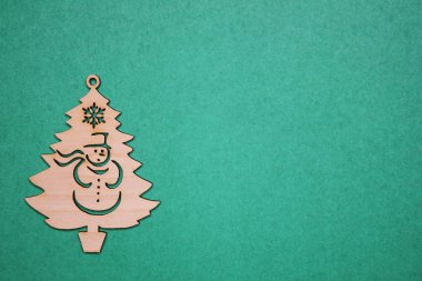 Yeşil bir arka plan üzerinde bir kardan adam ile Ahşap Noel ağacı heykelcik.