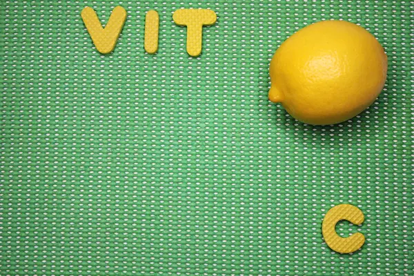 Limón fresco y letras VIT C sobre fondo verde —  Fotos de Stock