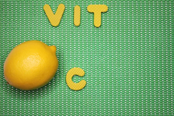 Limón fresco y letras VIT C sobre fondo verde —  Fotos de Stock