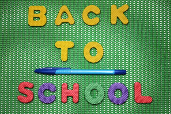 Powrót do szkoły słowa są wyłożone kolorowymi literami na zielonym tle obok pióra. — Zdjęcie stockowe
