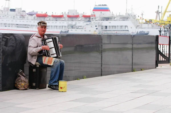 Vladivostok, Russie - 3 juin 2019 : Un vieil homme joue de l'accordéon sur le front de mer pour gagner sa vie . — Photo