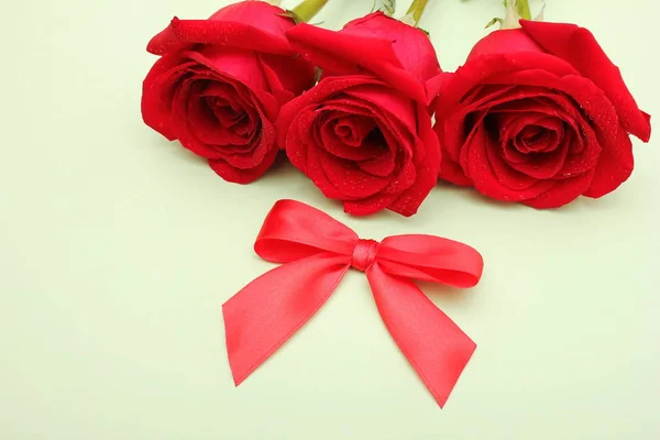 Tres rosas rojas con gotas de agua y un lazo rojo al lado. Tarjeta de cumpleaños feliz . — Foto de Stock