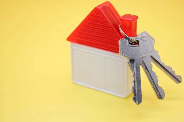 Hausschlüssel und ein Spielzeughaus. das Konzept des Immobilienerwerbs. — Stockfoto