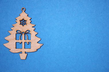 Ahşap figürlü, arka planda mavi bir hediye olan Noel ağacı. Yeşil Noel arka planı.