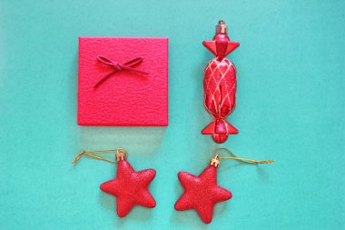 Noel beşiği. Kırmızı Noel oyuncakları ve kırmızı hediye kutusu yeşil arka plana yerleştirilir. Yukarıdan görünüşü.