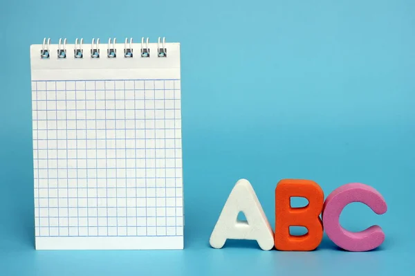 ABC- letters of the English alphabet on a blue background. Blank Notepad page