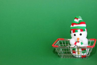 Oyuncak bir Noel Kardan Adam süpermarketten metal bir alışveriş sepetinde. Yeni yıl alışveriş konsepti.
