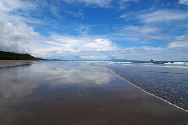 Playa El Coco, Nikaragua, aşırı düşük tide maruz plaj yansıyan parlak beyaz bulutlar ile.