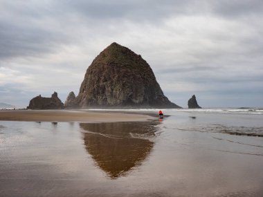 Kadın Haystack Rock top Beach, Oregon üzerinde fotoğraf çekimi.