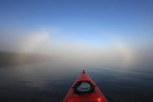 Piros kajak irány felé egy fényes fogbow. — Stock Fotó