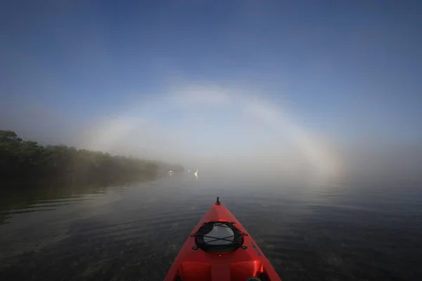 Κόκκινο καγιάκ κατευθύνεται προς ένα φωτεινό fogbow. — Φωτογραφία Αρχείου