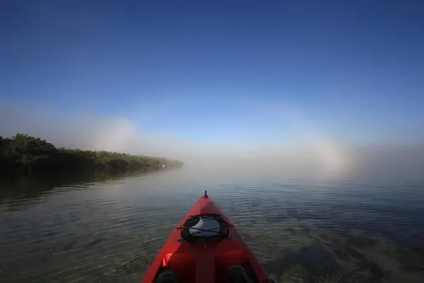 Parlak bir fogbow doğru kırmızı kayık başlık. — Stok fotoğraf